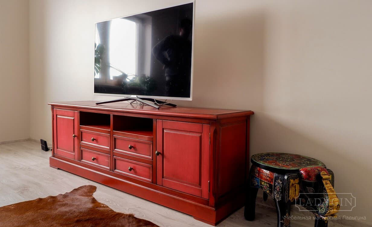 Красная деревянная тумба под телевизор в классическом стиле с 4 ящиками на цоколе в интерьере фото
