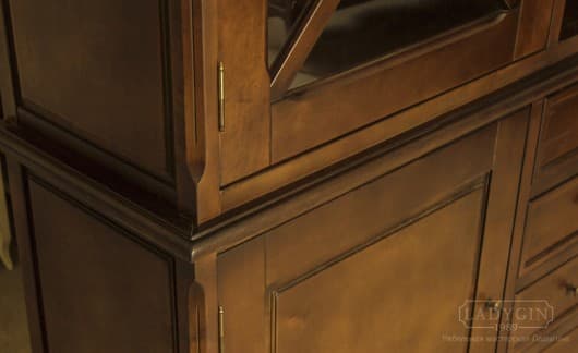 Классическая отделка высокого деревянного книжного шкафа в стиле прованс со стеклянными дверками на цоколе фото