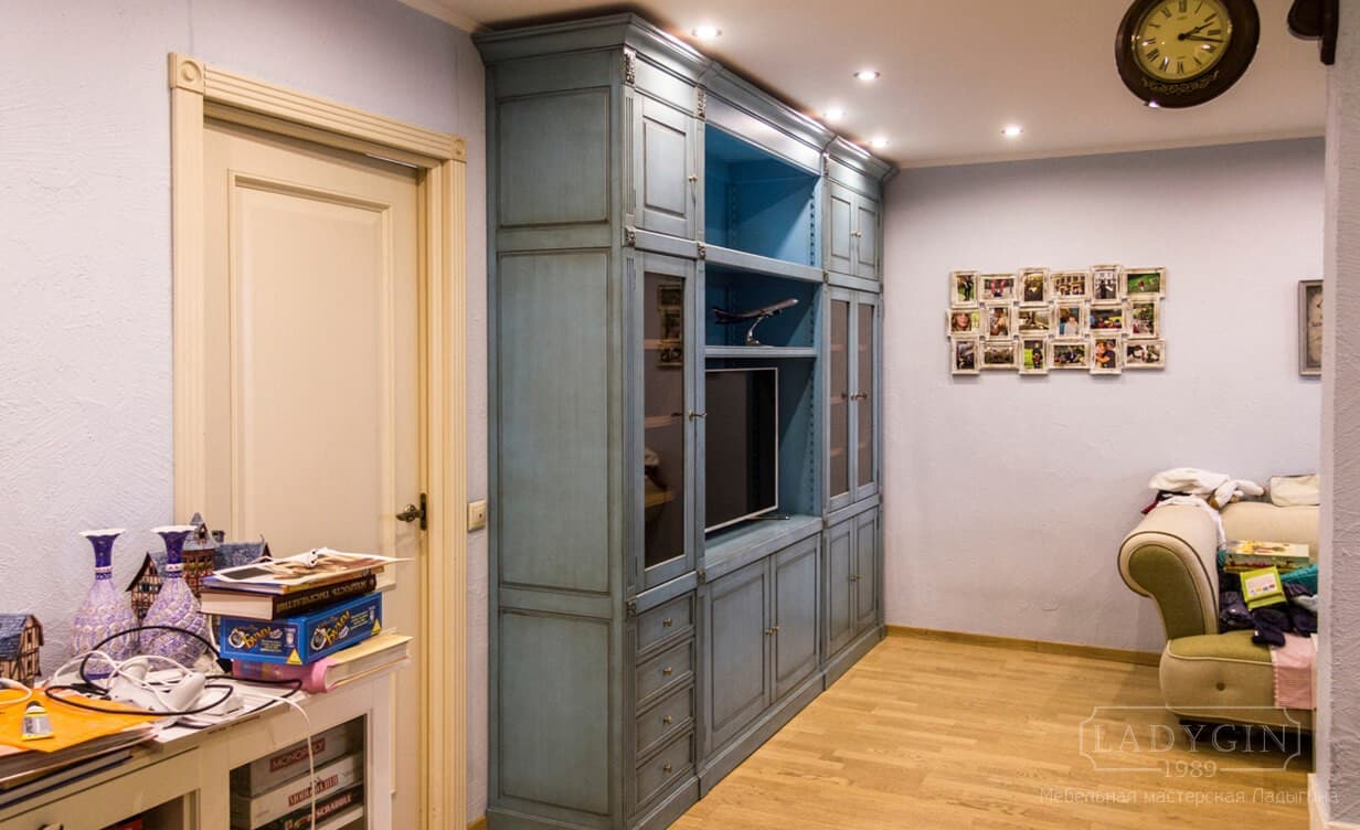 Синий деревянный книжный шкаф в классическом стиле с нишей под телевизор в интерьере прихожей фото