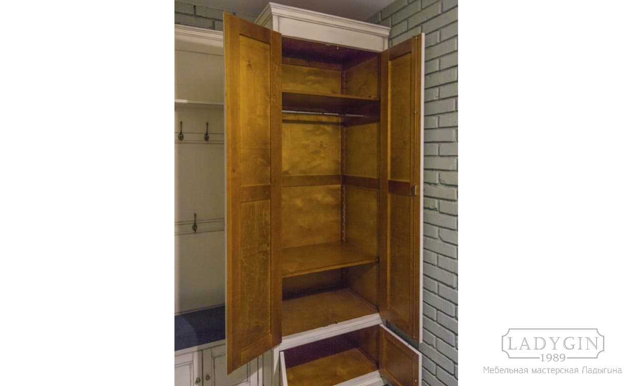 Наполнение шкафа белой узкой деревянной прихожей в классическом стиле из вешалки шкафа и пуфа-тумбы фото