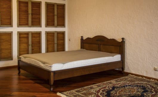 Коричневая двуспальная кровать из массива дерева в стиле прованс с высоким резным изголовьем в интерьере спальни фото