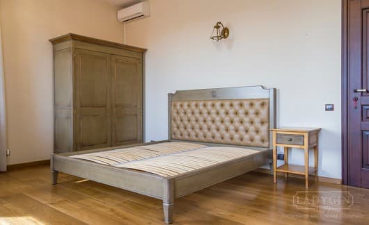 Двуспальная кровать из массива дерева с мягким высоким изголовьем из экокожи во французском стиле в интерьере комнаты фото