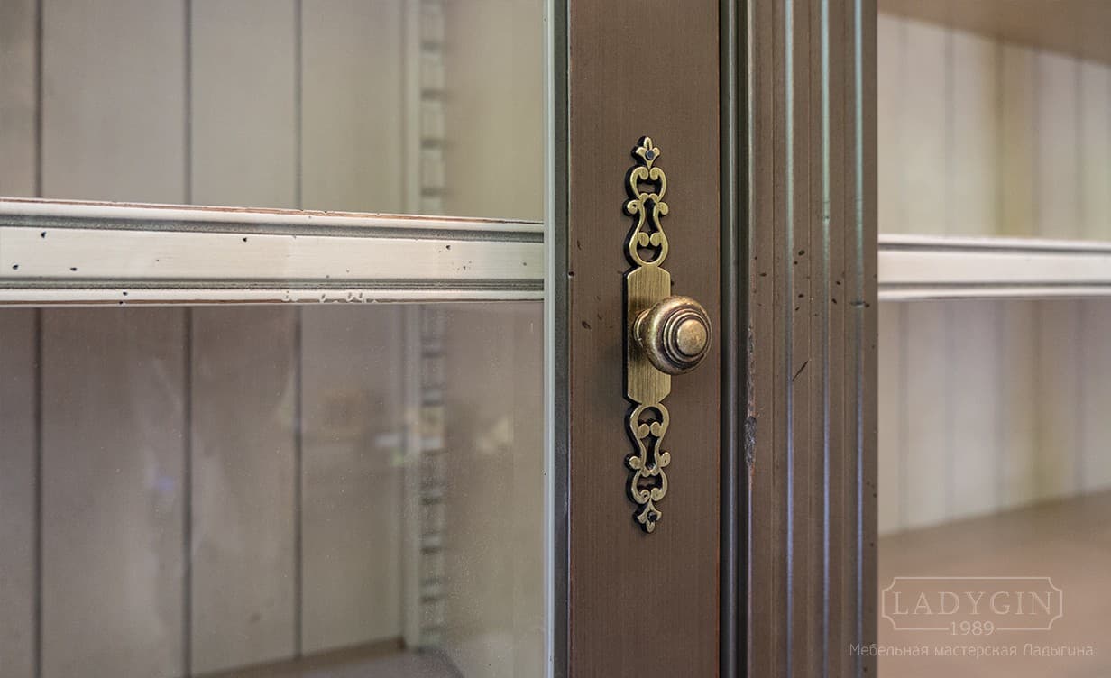 Латунная ручка деревянной модульной библиотеки в классическом стиле с лестницей полками и стеклянными дверками фото