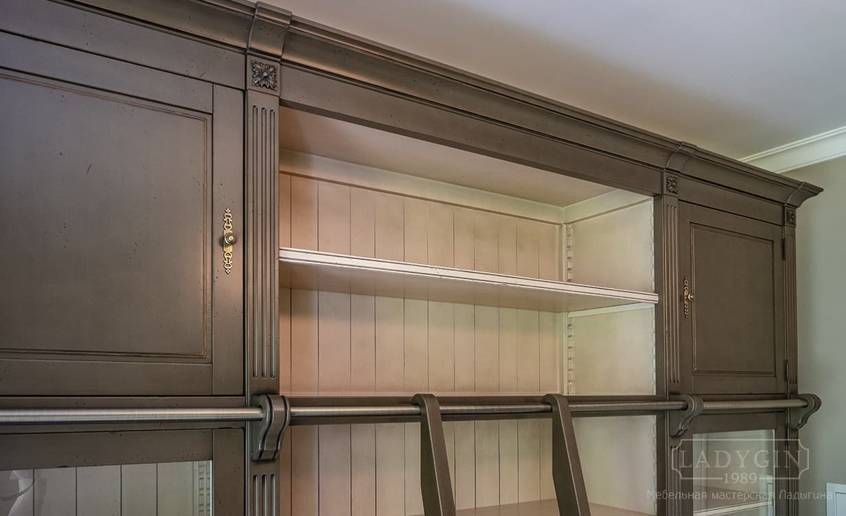 Карниз деревянной модульной библиотеки в классическом стиле с лестницей полками и стеклянными дверками фото
