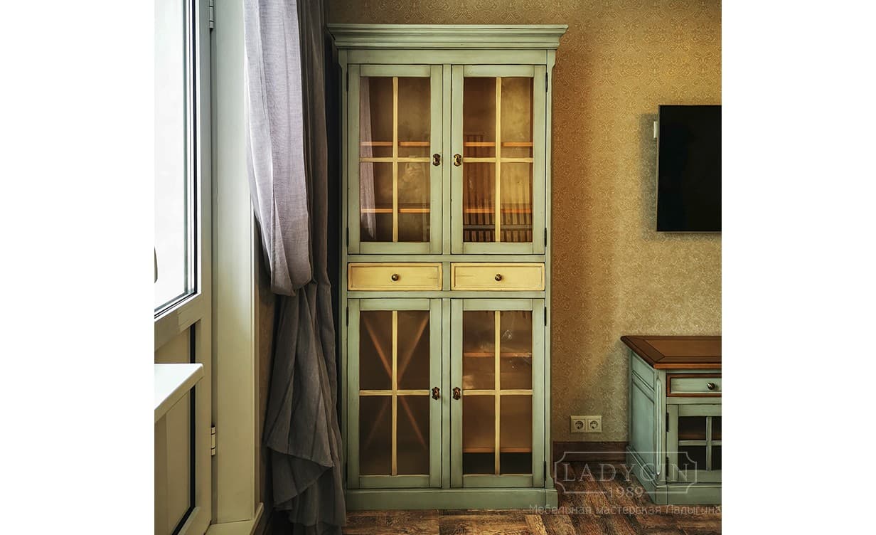 Высокая деревянная витрина в классическом стиле с 2 ящиками и стеклянными дверками в интерьере фото