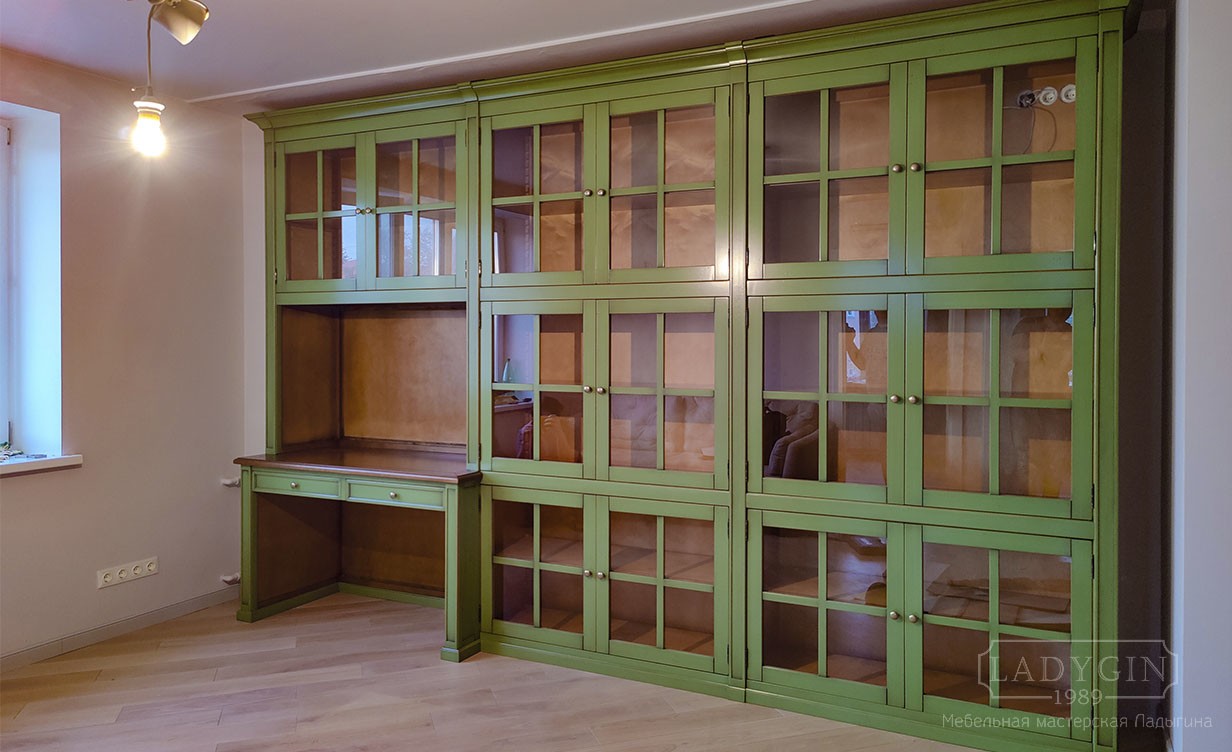 Зелёная библиотека из дерева в классическом стиле со стеклянными дверцами и рабочим местом в интерьере фото